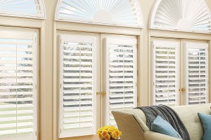White shutters over windows looking out at back yard with trees and grass